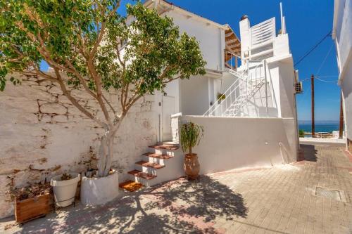 a white building with a tree next to a wall at Athena's View in Megalochori
