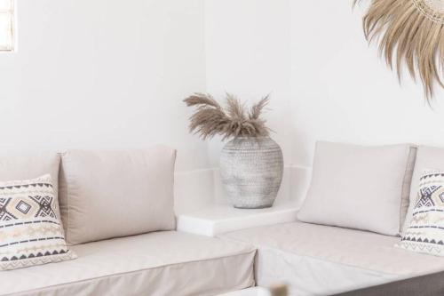 a white living room with a couch and a potted plant at Athena's View in Megalochori