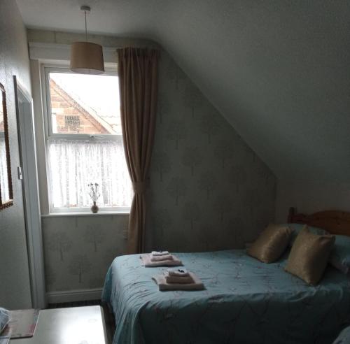 a bedroom with a bed and a window with towels on it at The Sandgate in Skegness