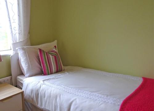 a small bedroom with a white bed with a window at Mary Naoise Holiday Home by Trident Holiday Homes in Lettermacaward