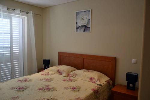 ein Schlafzimmer mit einem Bett und einem Bild an der Wand in der Unterkunft Moradia Fantástica com Piscina a 5 min da Praia in Monte Gordo