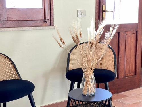 two chairs and a table with a vase with grass at La Casa Grande di Pantelleria in Pantelleria