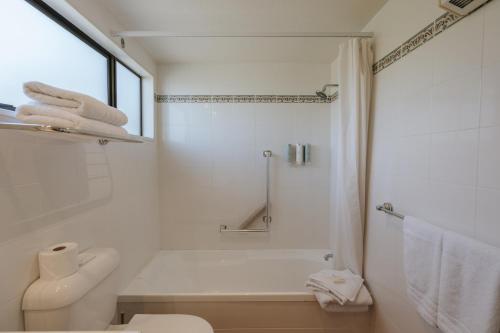a white bathroom with a shower and a toilet at Edgewater Hotel in Wanaka