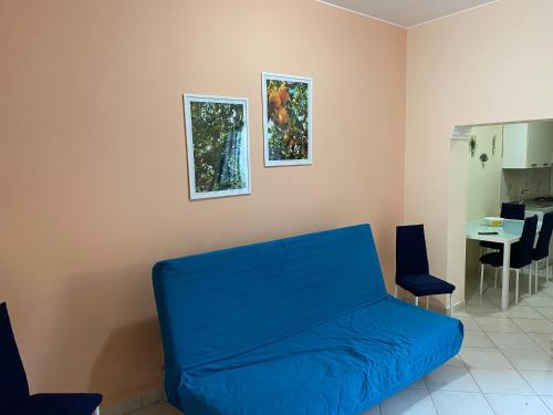 a living room with a blue couch and two pictures on the wall at Casa degli Agrumi in Capo dʼOrlando