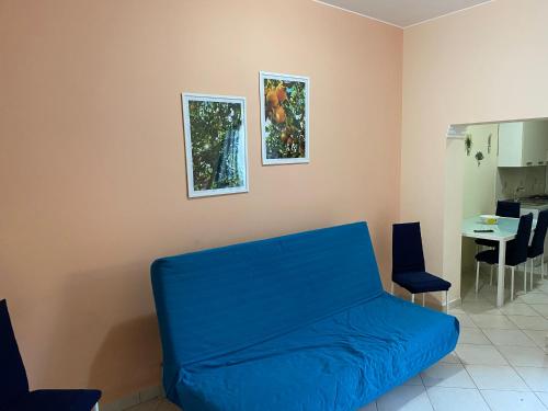 sala de estar con sofá azul y 2 cuadros en la pared en Casa degli Agrumi, en Capo dʼOrlando