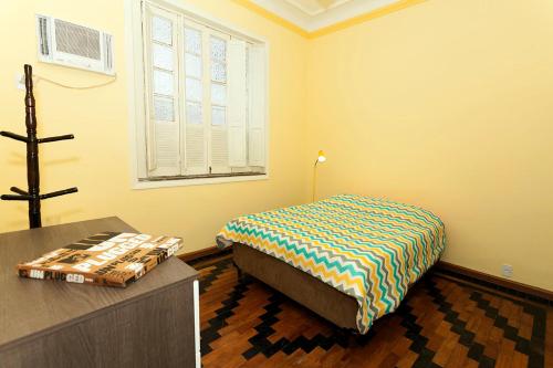 Schlafzimmer mit einem Bett, einem Tisch und einem Fenster in der Unterkunft Casa Saga - All Suites in Rio de Janeiro