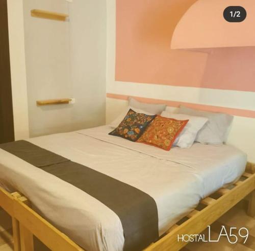 a bed with a white comforter and pillows at Hostal La 59 in Mérida