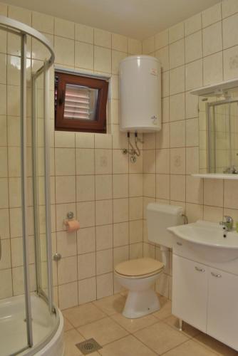 La salle de bains est pourvue de toilettes, d'un lavabo et d'une douche. dans l'établissement Apartments Niko, à Sukošan