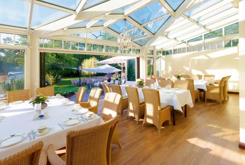 ein Restaurant mit weißen Tischen und Stühlen und Fenstern in der Unterkunft Tiemann's Hotel in Stemshorn