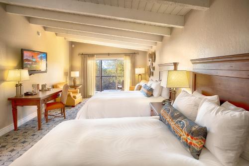 a hotel room with three beds and a desk at Westward Look Wyndham Grand Resort & Spa in Tucson
