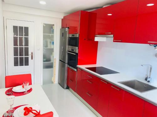 a red kitchen with white counters and red cabinets at Entire apartment in Lisbon plus Car in Lisbon