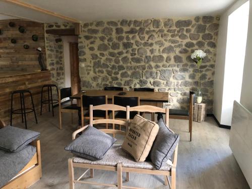 Cette chambre est dotée d'une table, de chaises et d'un mur en pierre. dans l'établissement Appartement 6 personnes valgorge, à Valgorge