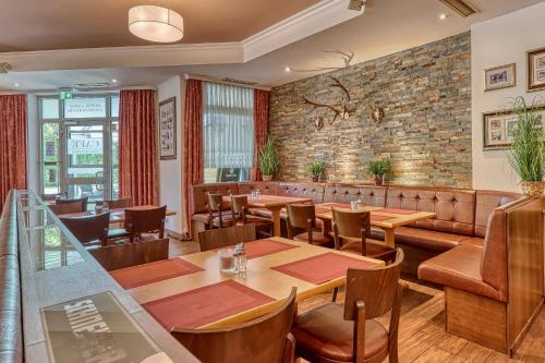 a restaurant with tables and chairs and a brick wall at Kurpension Freudenstein in Bad Füssing