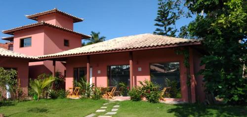 een roze huis met een dak bij Hospedaria Oitis in Búzios