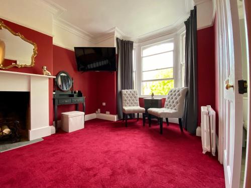 a red living room with two chairs and a fireplace at Blenheim Guest House in York