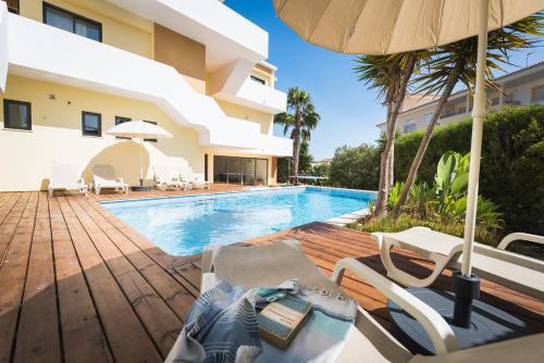 a swimming pool with chairs and an umbrella next to a building at Villa Boho in Lagos