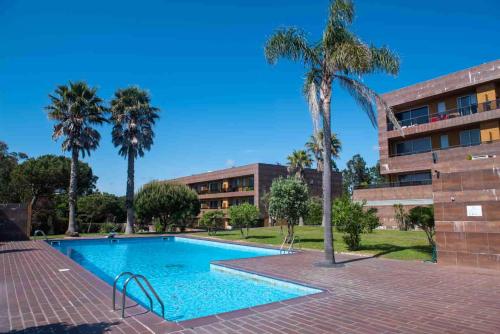 a swimming pool in front of a building with palm trees at Charming Apartment in Marmoiral