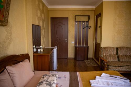 a bedroom with a bed and a couch and a door at Family Hotel Kolorit Old Tbilisi in Tbilisi City