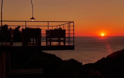 a sunset over the ocean with two chairs on a balcony at Sunrise Garden Hills in Makrirrákhi