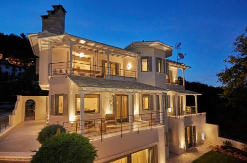 a large white house with a porch at night at Sunrise Garden Hills in Makrirrákhi