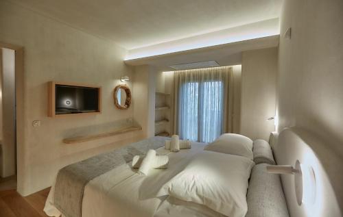 a bedroom with a large white bed and a television at Sunrise Garden Hills in Makrirrákhi