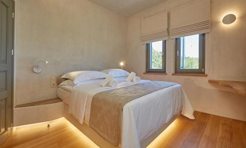 a bedroom with a bed with white sheets and a window at Sunrise Garden Hills in Makrirrákhi
