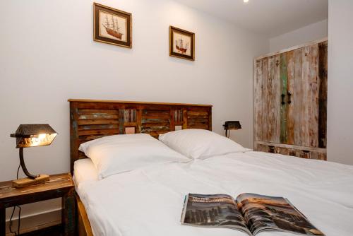 a bedroom with a white bed with a book on it at Ferienwohnung Inselblick in Hörnum