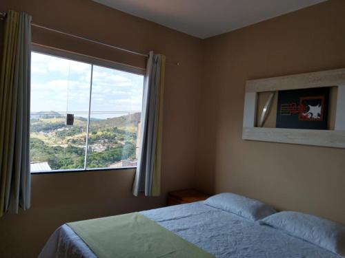 um quarto com uma cama e uma grande janela em CASA ACONCHEGANTE em São Lourenço