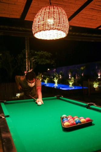a man playing pool at a pool table at Pousada TeMoana in Ubatuba