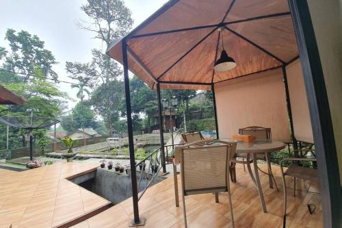 a patio with a table and chairs and an umbrella at Private Villa Dekke Boru, Bogor in Bogor