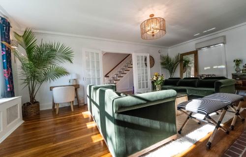a living room with green furniture and a staircase at Buttonwood Boutique Hotel in West Cape May
