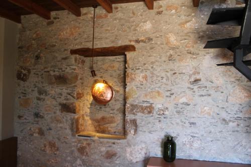 una luce appesa a un muro con un muro di pietra di INO III Domus SWIMSPA by Amigdalokefali Elafonissi ad AmigdhalokeFálion