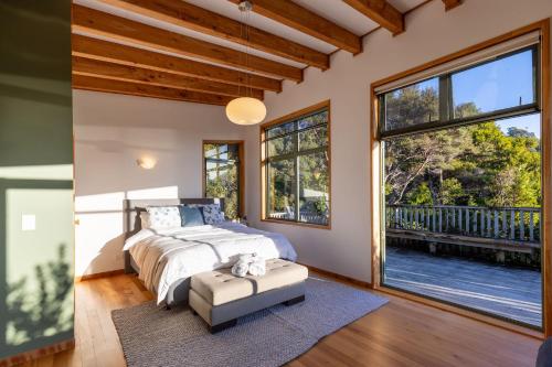 a bedroom with a bed and a large window at Karu ō te Kiwi in Pakawau