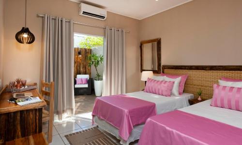 a bedroom with two beds with pink sheets at Pousada Rio Claro in Poconé