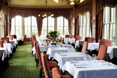 a restaurant with white tables and chairs and windows at Chateau Yering in Yarra Glen