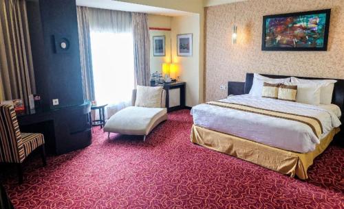 a hotel room with a large bed and a chair at Swiss-Belhotel Silae Palu in Palu