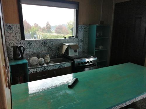 uma cozinha com uma bancada verde e uma janela em Casa Pascual em Dalcahue