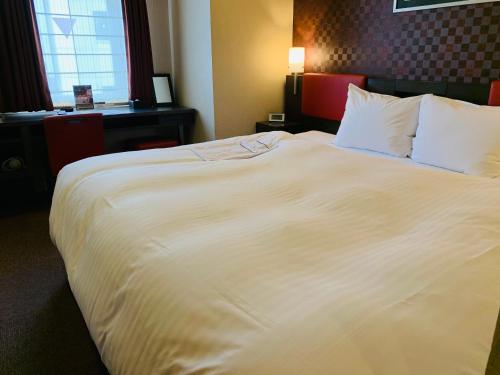 a large white bed in a hotel room at Smile Hotel Nagoya Sakae in Nagoya