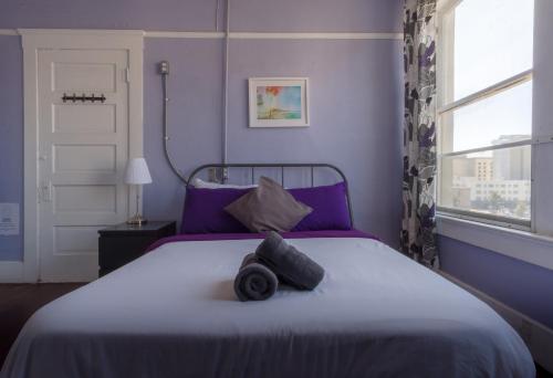 a bedroom with a bed with purple walls and a window at Lucky D's Youth and Traveler's Hostel in San Diego