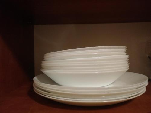 a stack of white plates and bowls on a table at CAPPUCCINO CENTRUM Apartman in Kaposvár