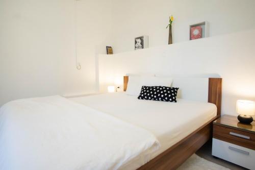 a white bed with a black and white pillow on it at Kuća za odmor Vladimir in Matulji