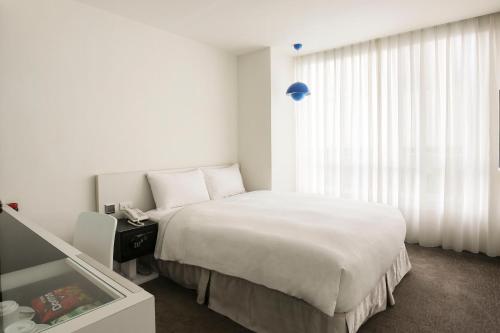 a white bedroom with a bed and a window at CityInn Hotel Taipei Station Branch III in Taipei