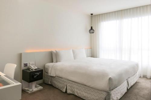 a white bedroom with a large bed and a window at CityInn Hotel Taipei Station Branch III in Taipei