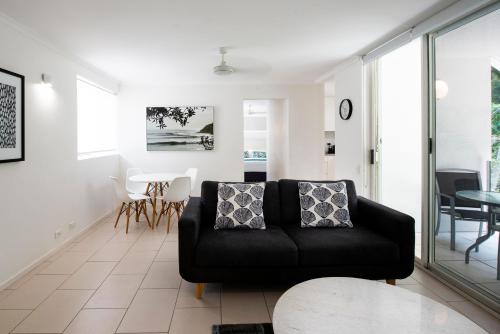 a living room with a black couch and a table at SandCastles Noosa in Noosa Heads