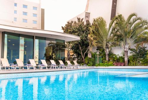 une piscine avec des chaises et un bâtiment dans l'établissement Crown Promenade Perth, à Perth