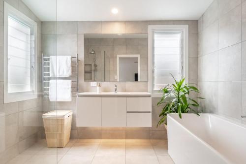 a bathroom with a tub and a sink and a mirror at Banksia - Lennox Head in Lennox Head