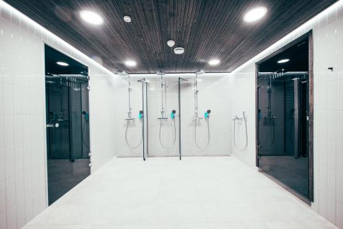 a bathroom with four shower stalls and a row of mirrors at The Folks Hotel Konepaja in Helsinki