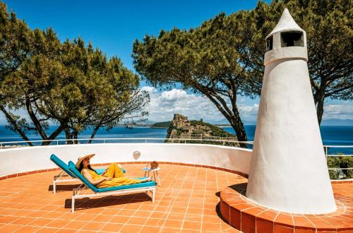 a woman laying in a chair next to a lighthouse at Villa Livia in Ischia