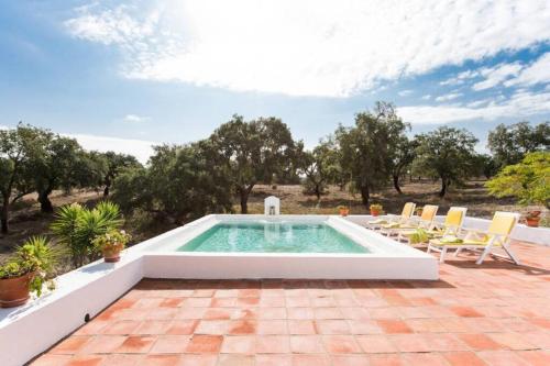 an outdoor swimming pool with chairs and a swimming poolvisor at MONTE DO CORTIÇO in Arraiolos