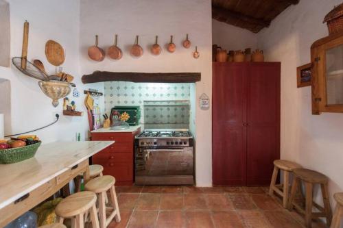 a kitchen with a stove and a counter with stools at MONTE DO CORTIÇO in Arraiolos